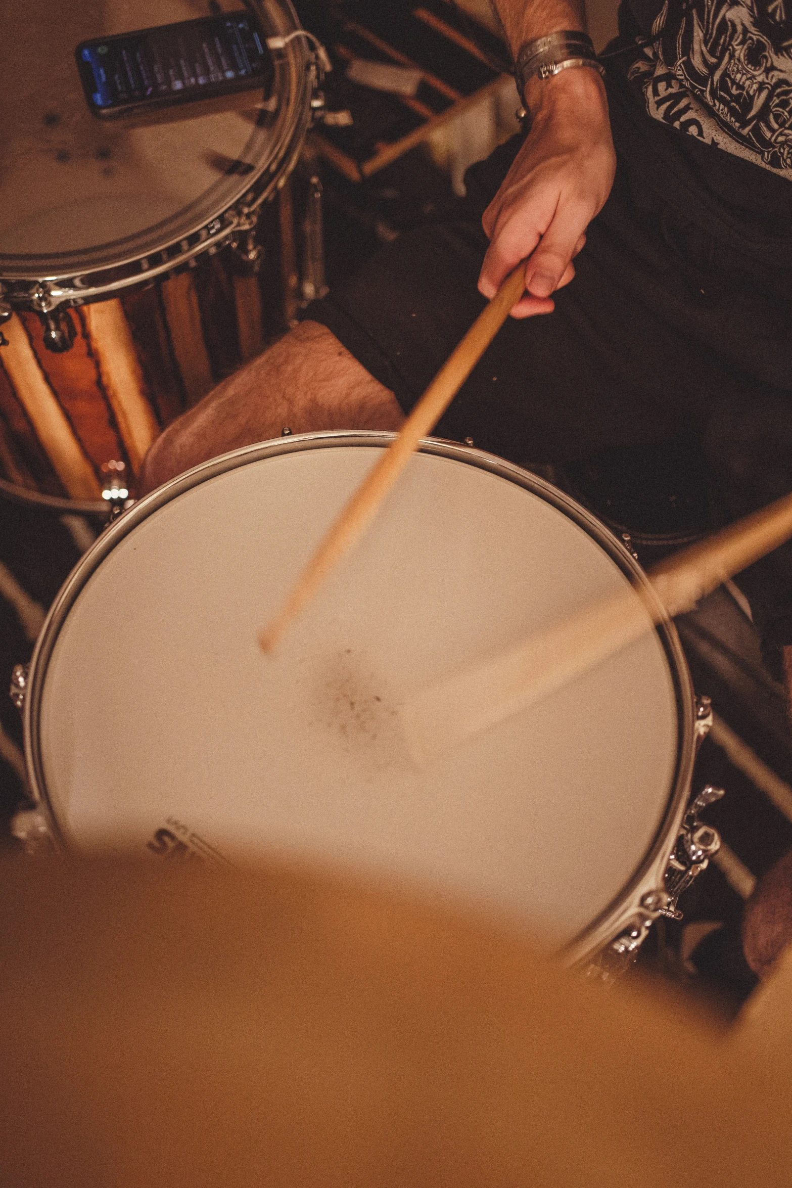 person sitting behind some drums playing it