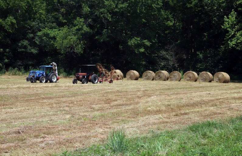a tractor drives near hay bales in the middle of a field