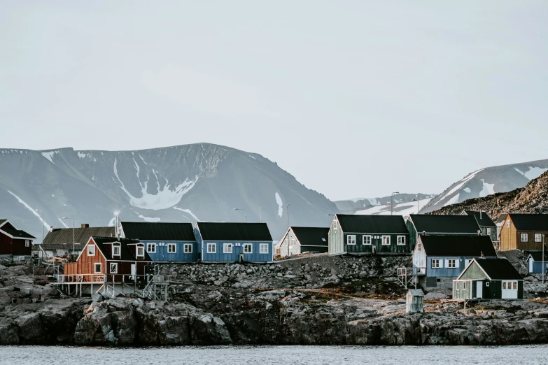 a row of houses next to mountains with a body of water