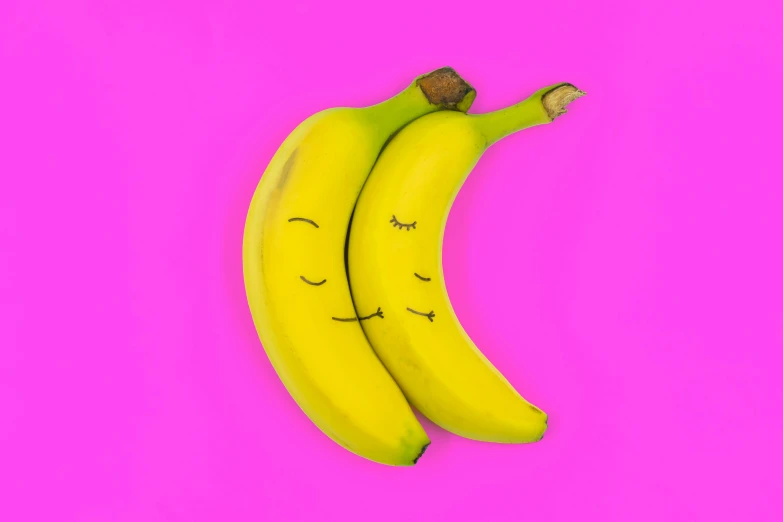 two bananas with closed eyes on a pink background