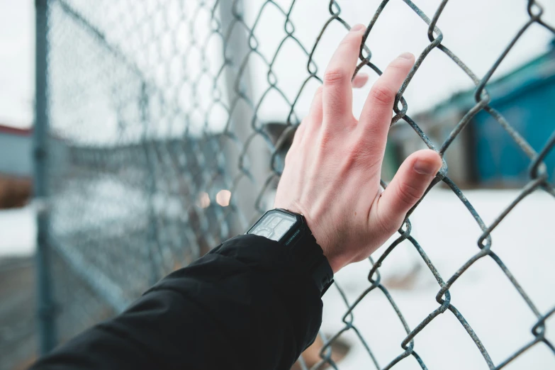 a hand reaching for the top of a fence