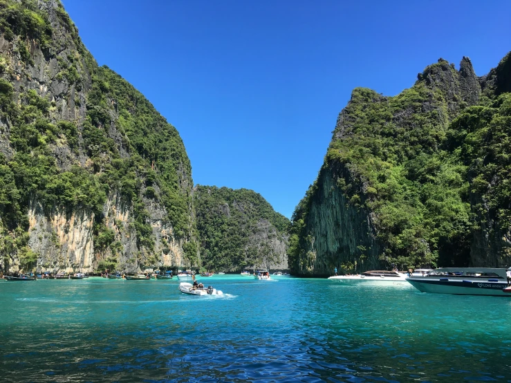 a person in a small boat on a river near some cliffs