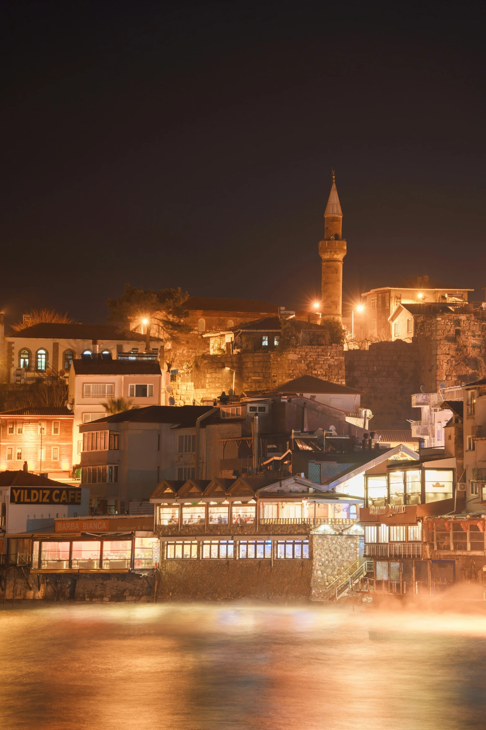 an old town with a tower and lights at night