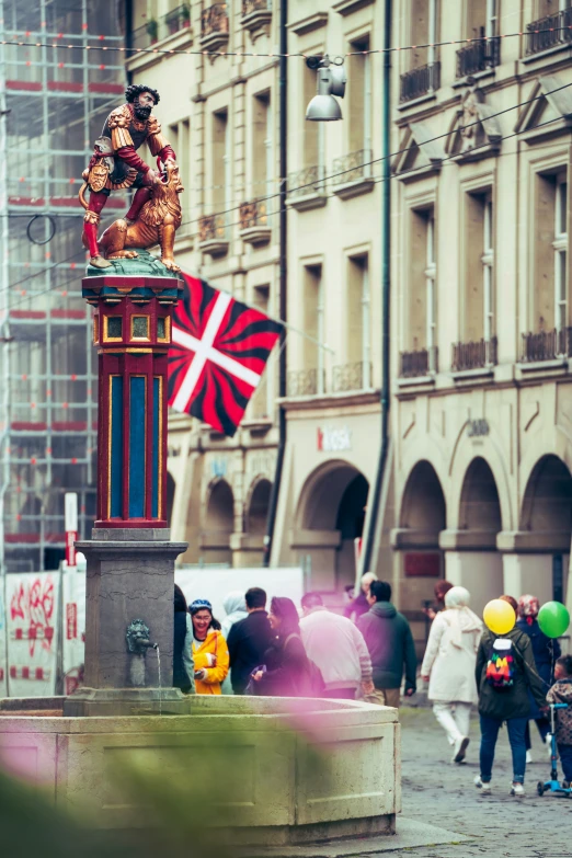 a clock tower sits in the middle of a square while people stand around it