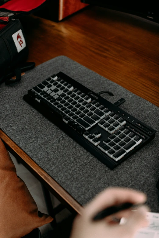 a black and gray keyboard resting on top of a black and grey desk