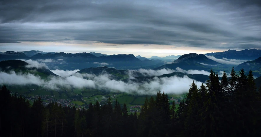 a landscape of mountains with some clouds in the foreground