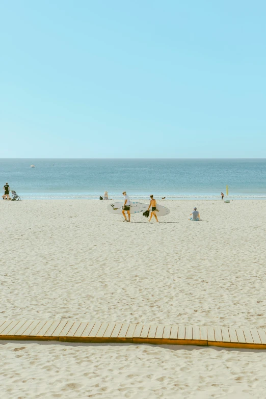 people on a beach near water with several kites