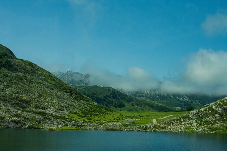 water in a valley with mountains and clouds