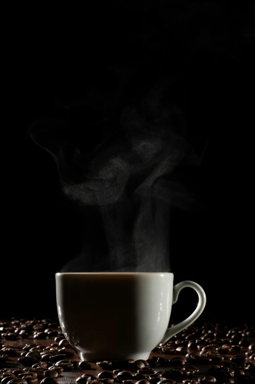 a steaming cup of coffee on top of coffee beans