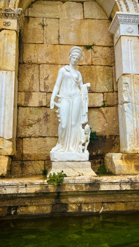 a statue of a lady holding a fan against a wall