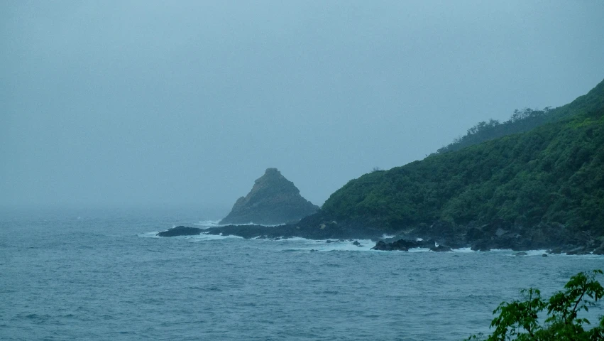 a mountain next to a body of water on a hazy day