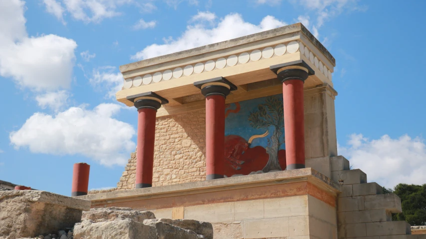 a pillar with columns painted on it under a cloudy blue sky