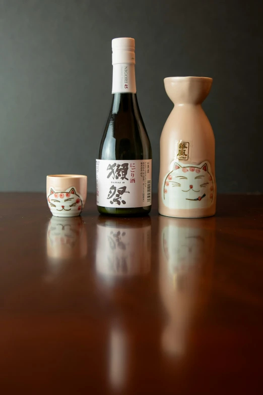 a brown bottle next to two cups on top of a wooden table