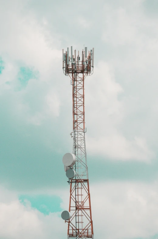 three different antennas sitting on top of a tall tower