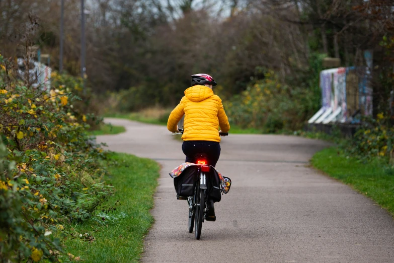 person in yellow jacket riding a bike down a road