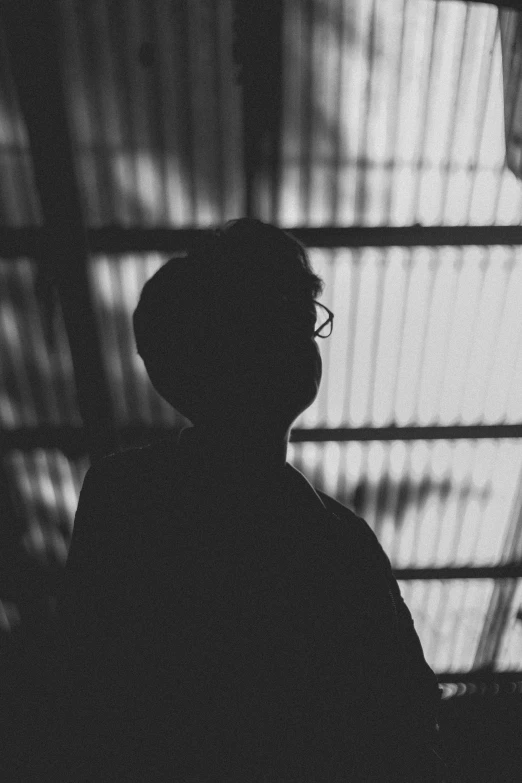 a man wearing glasses sitting in a dark room