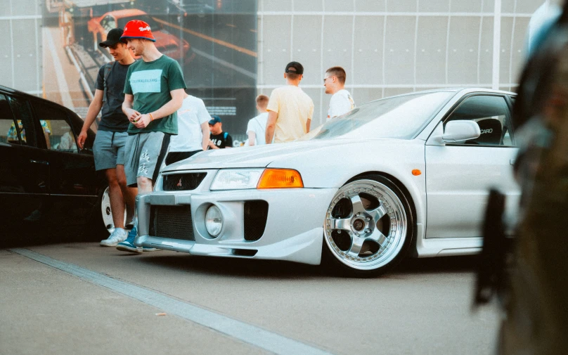 a group of young men gathered around a white car