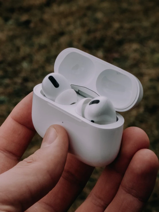 an individual holds the ear buds to hear it