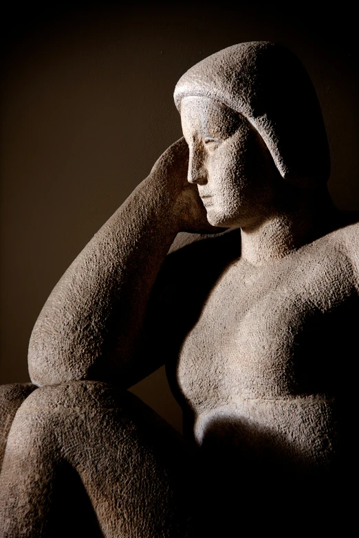 a statue sitting in the shadows of a wall