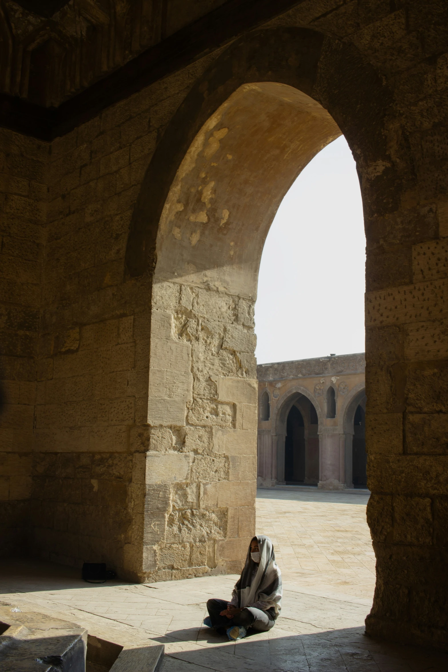 a woman in a veil sits outside a arch