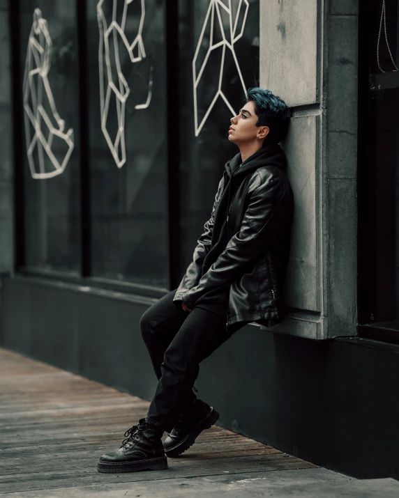 a man leaning on the side of a building