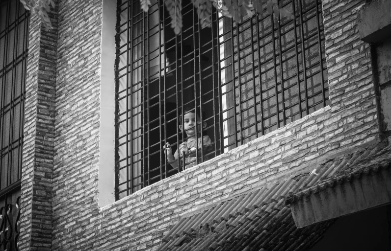 a black and white po of a man taking a picture out a window