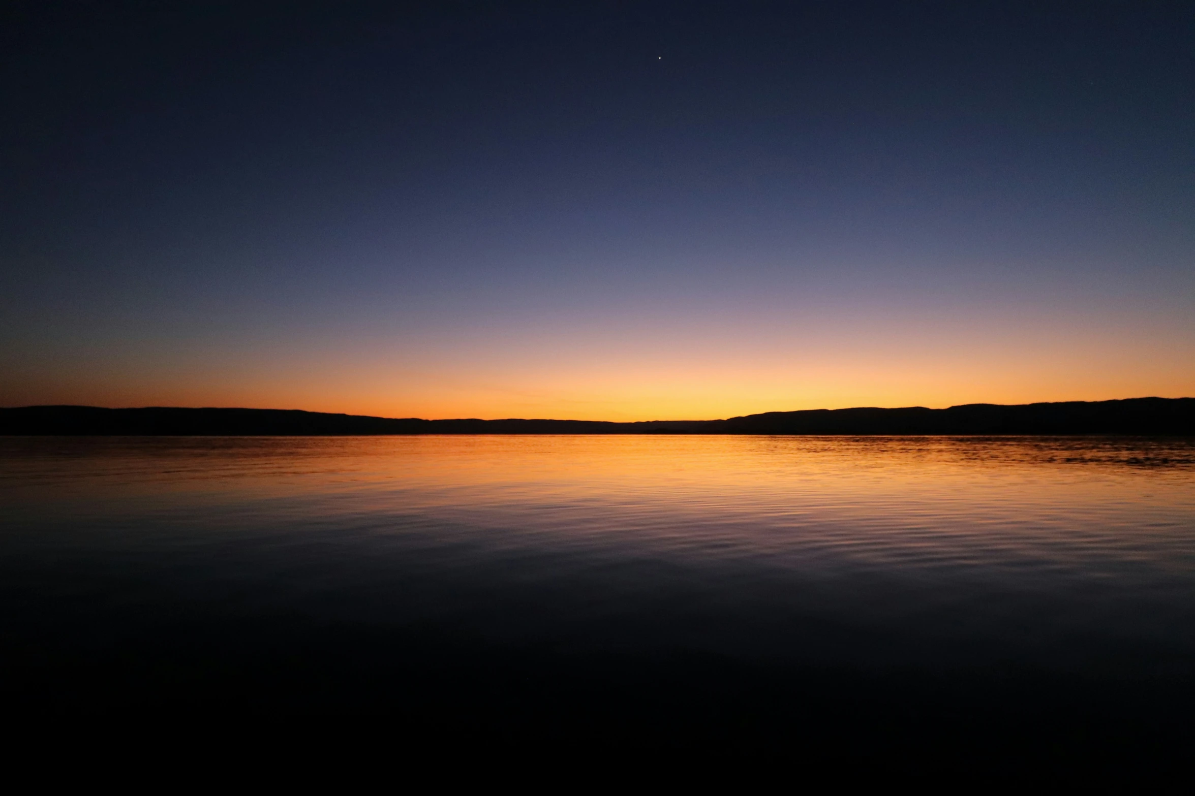 sunset over water with mountains in the background