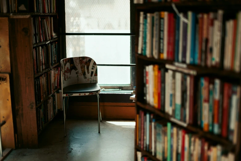 an open liry with a chair by the window and lots of books