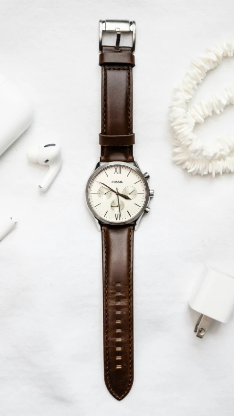 the watch has an all white dial and brown leather strap