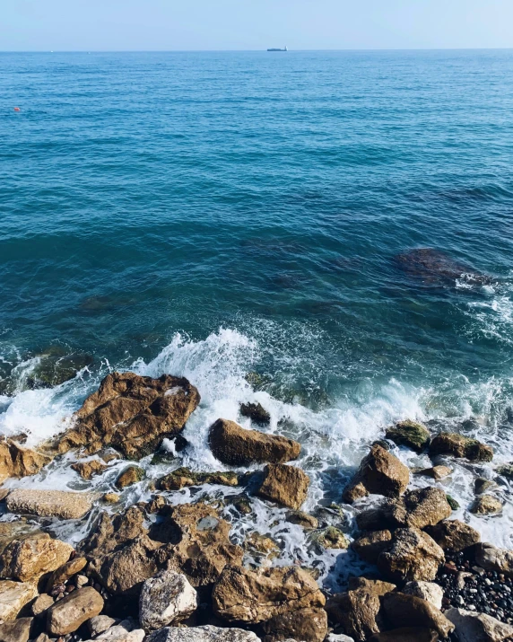 a man standing on top of a rock next to the ocean