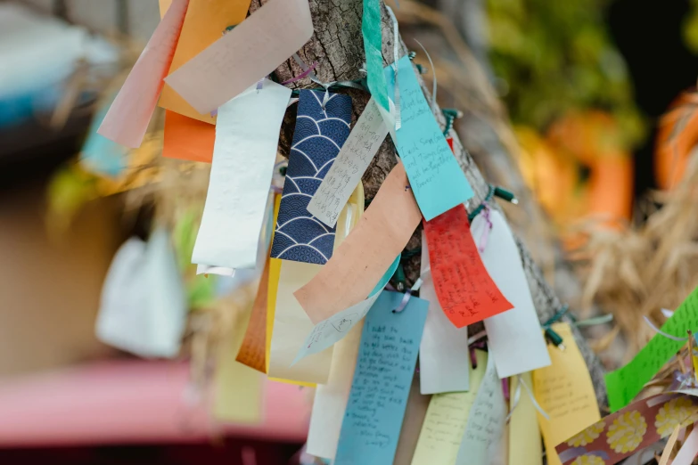 a tree with many colorful ribbons hanging from it's nches