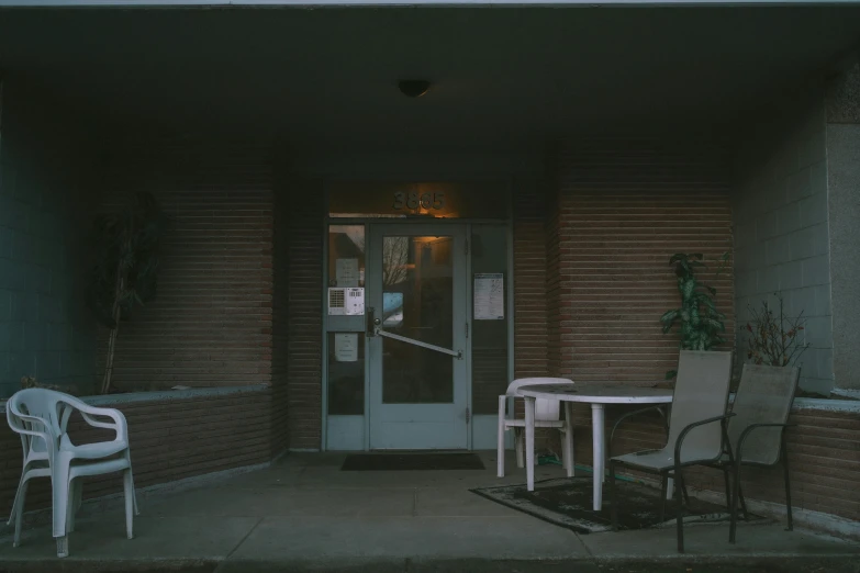 two patio chairs sitting on a porch next to an open door