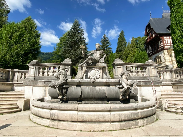 a large fountain with statues next to trees