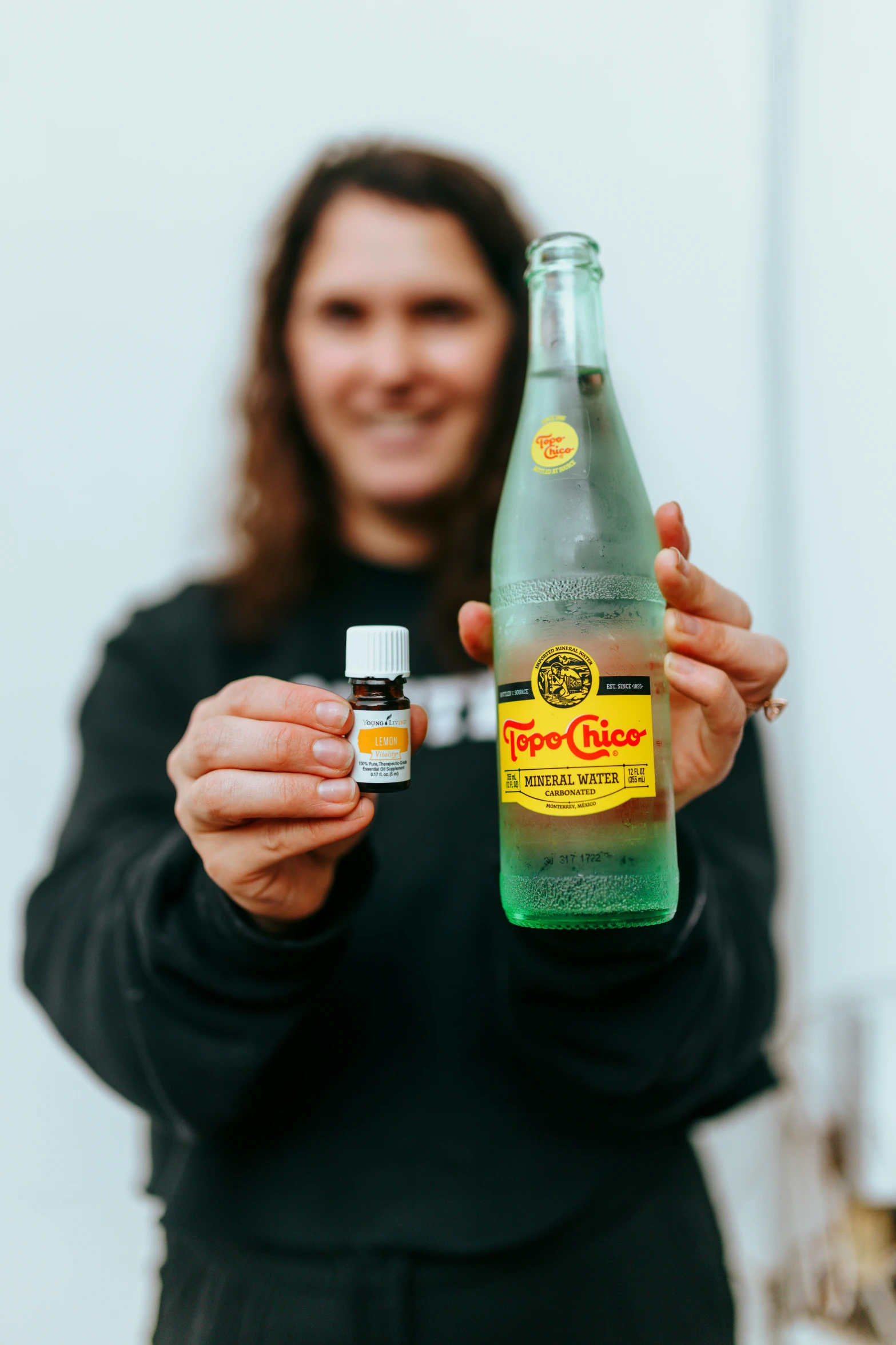 a person holds up an empty bottle and an essential oil