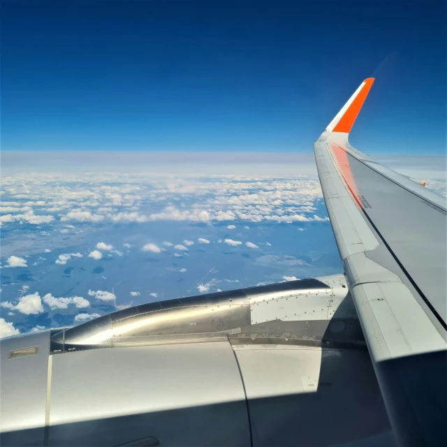 a view out an airplane window looking at the wing and clouds