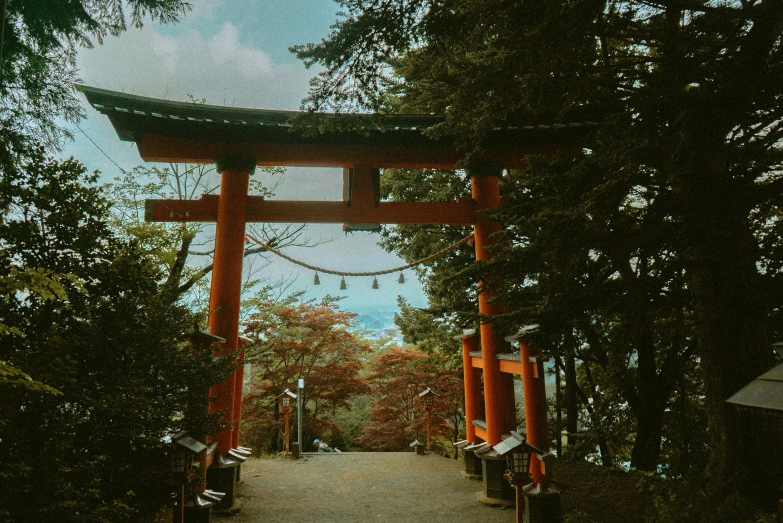 a path through a group of trees that has an overhanging asian gate