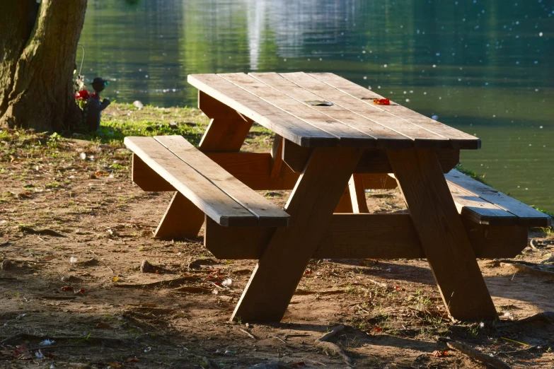 a picnic table with benches in the background by a lake