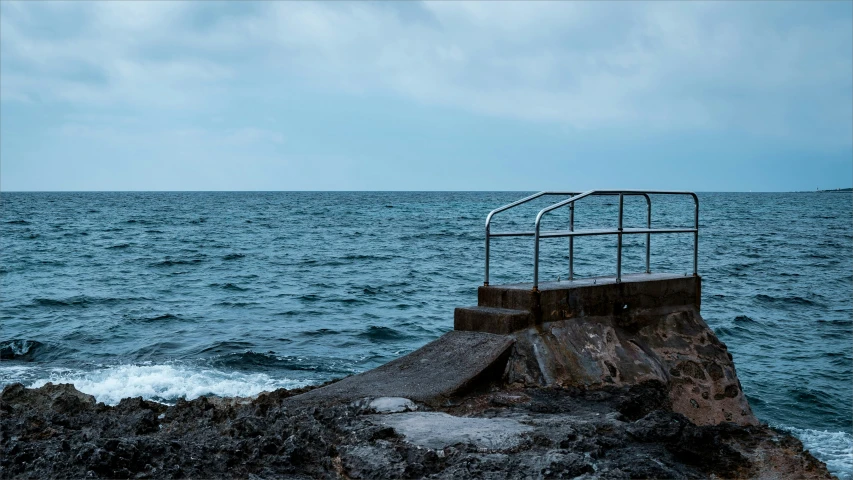 an ocean view with some waves crashing against a small rock wall