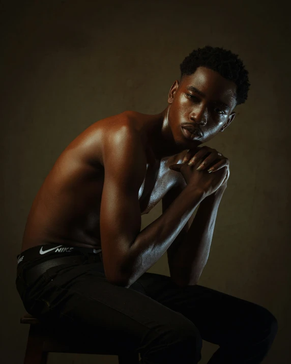 a male in a white shirt is sitting on a stool