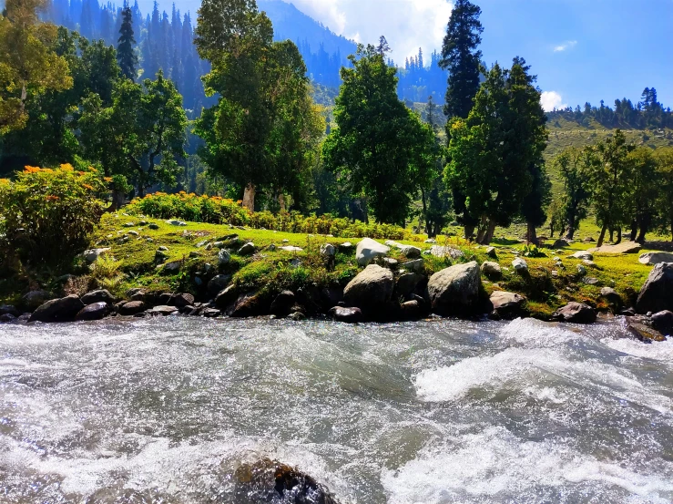 small boat out in a river, with mountains and greenery in the background