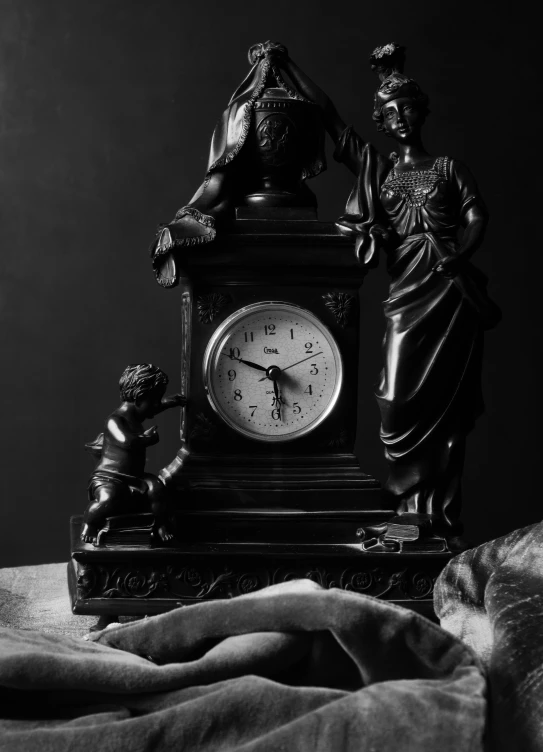 an antique black clock sits on a blanket