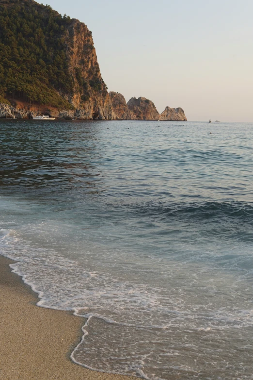 a beach next to an ocean with rock formations in the background