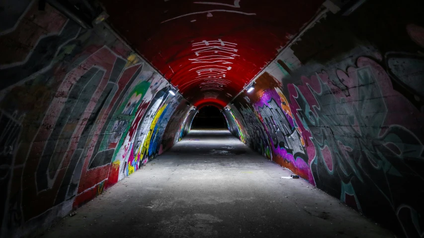 a long narrow corridor covered with graffiti at night