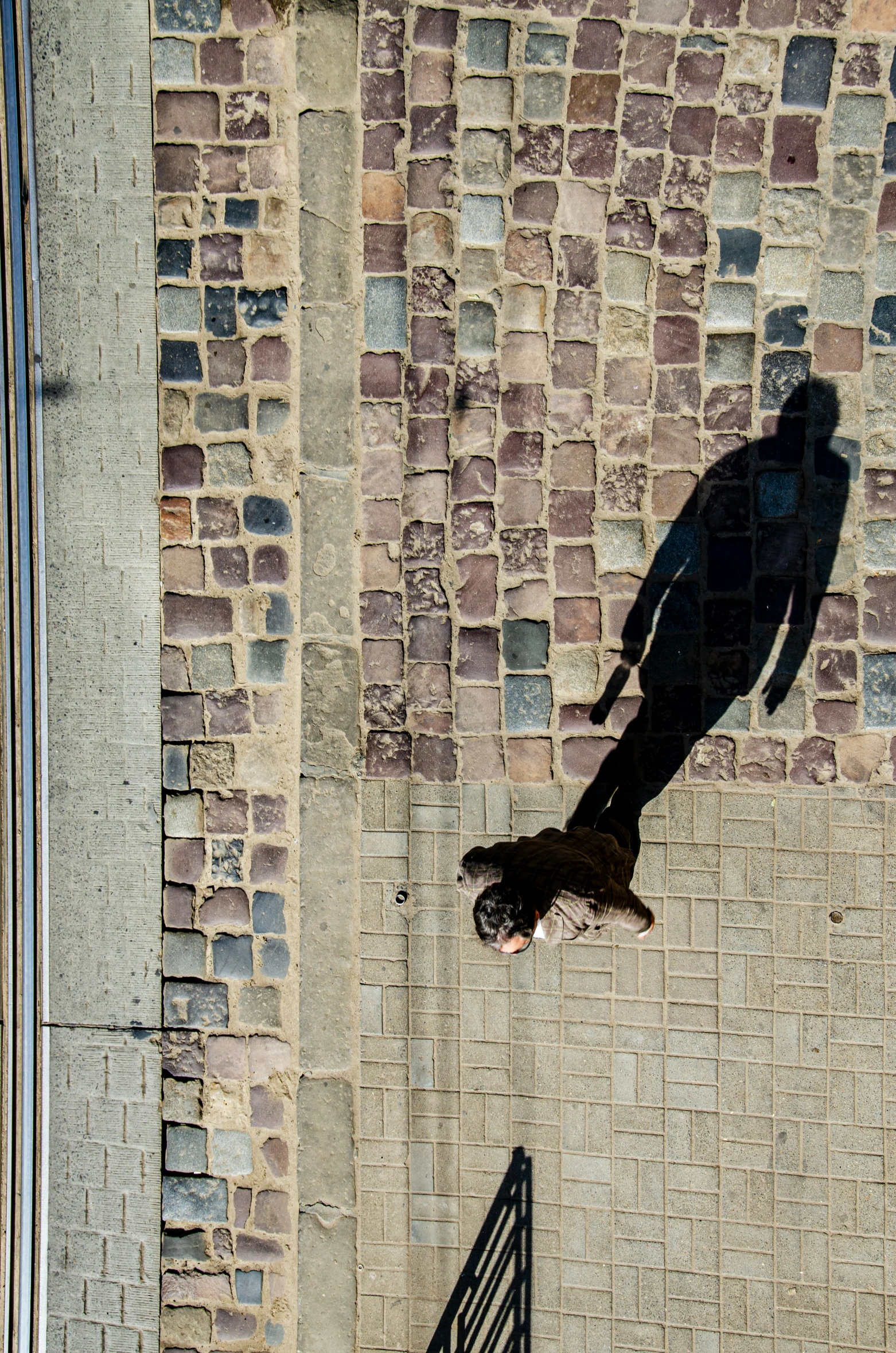 shadow on wall of black iron gate near a bench