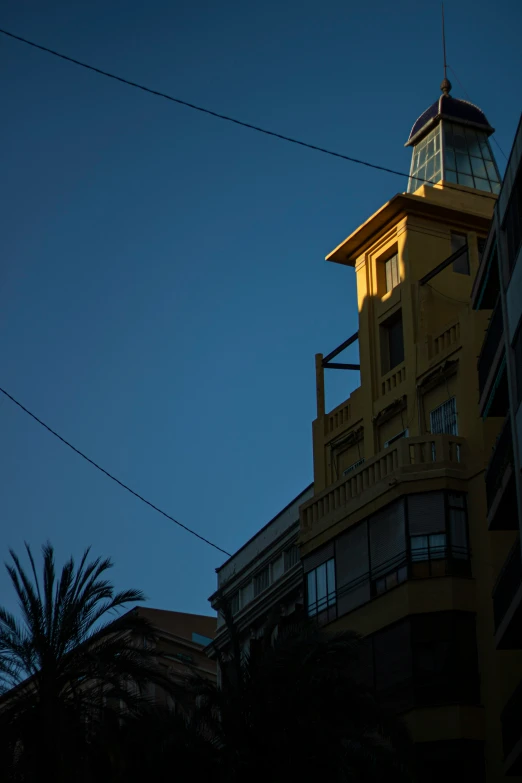 the top of a tall yellow building with a clock at the top