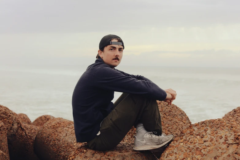 a man sitting on top of rocks near the water