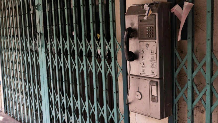 old fashioned telephone on the side of a green fence