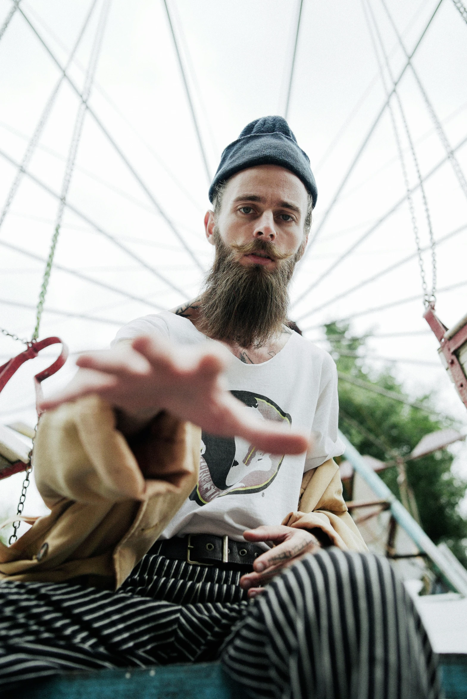 a bearded man with a cap and striped pants on a boat