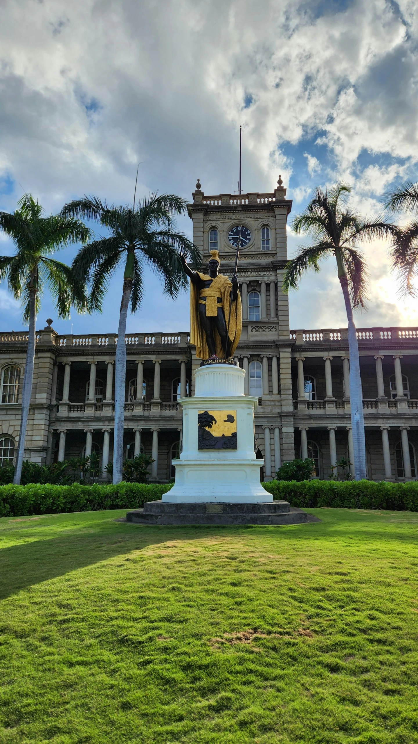 large building with statues on lawns near palm trees