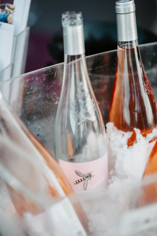 bottles of pink wine in ice sitting inside an empty tub